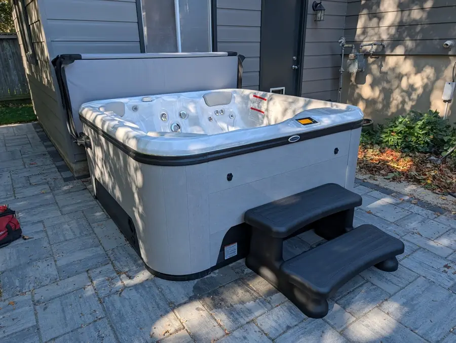 New hot tub set on an interlock patio with steps in Kitchener