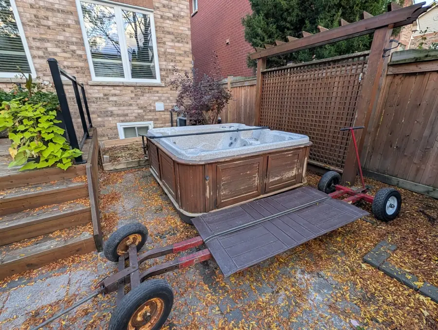 Old wood-frame hot tub on a dolly and ramp before removal in Mississauga